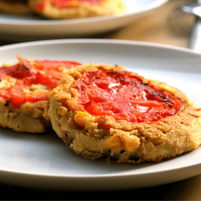 Tomato, chive and chickpea pancakes served warm on a plate